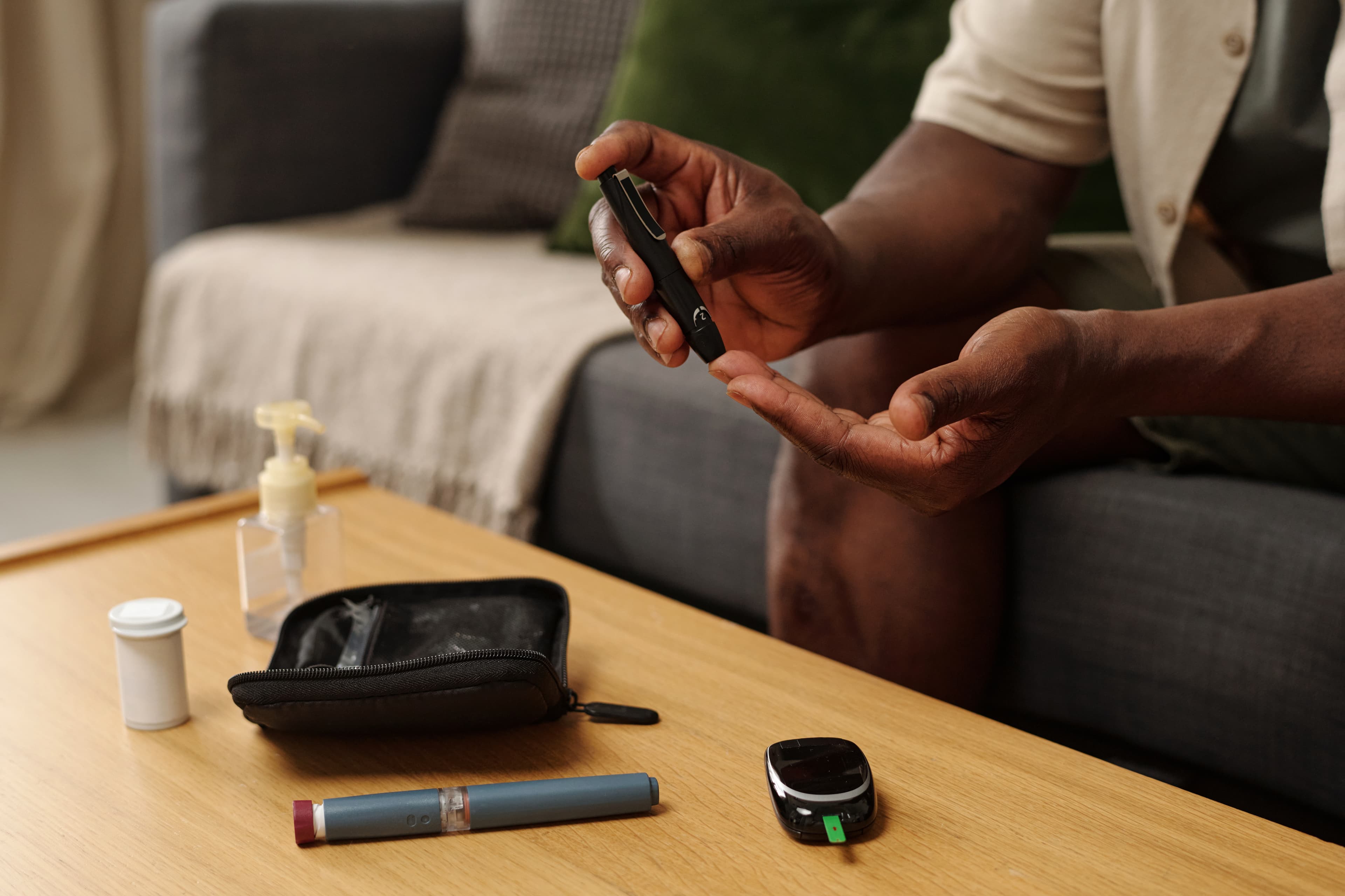 Person using a lancet pen to prick their finger for a blood glucose test at home.