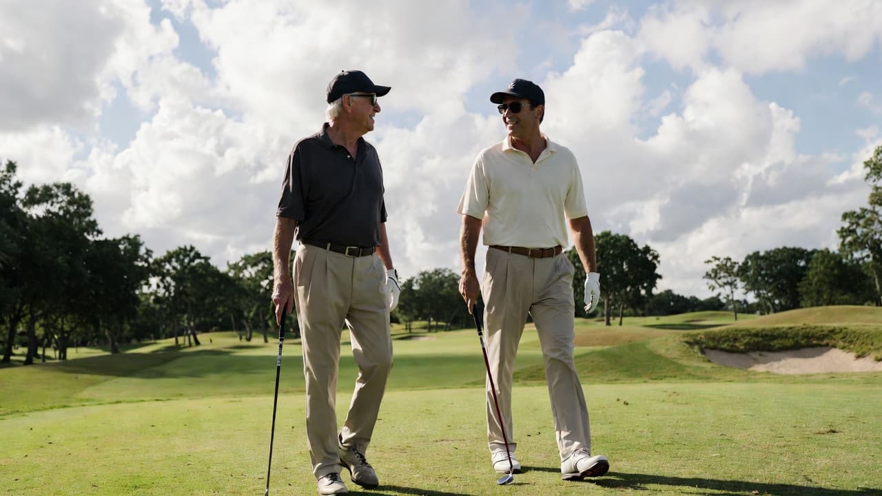 Two men of different ages walk together on a golf fairway under a partly cloudy sky.